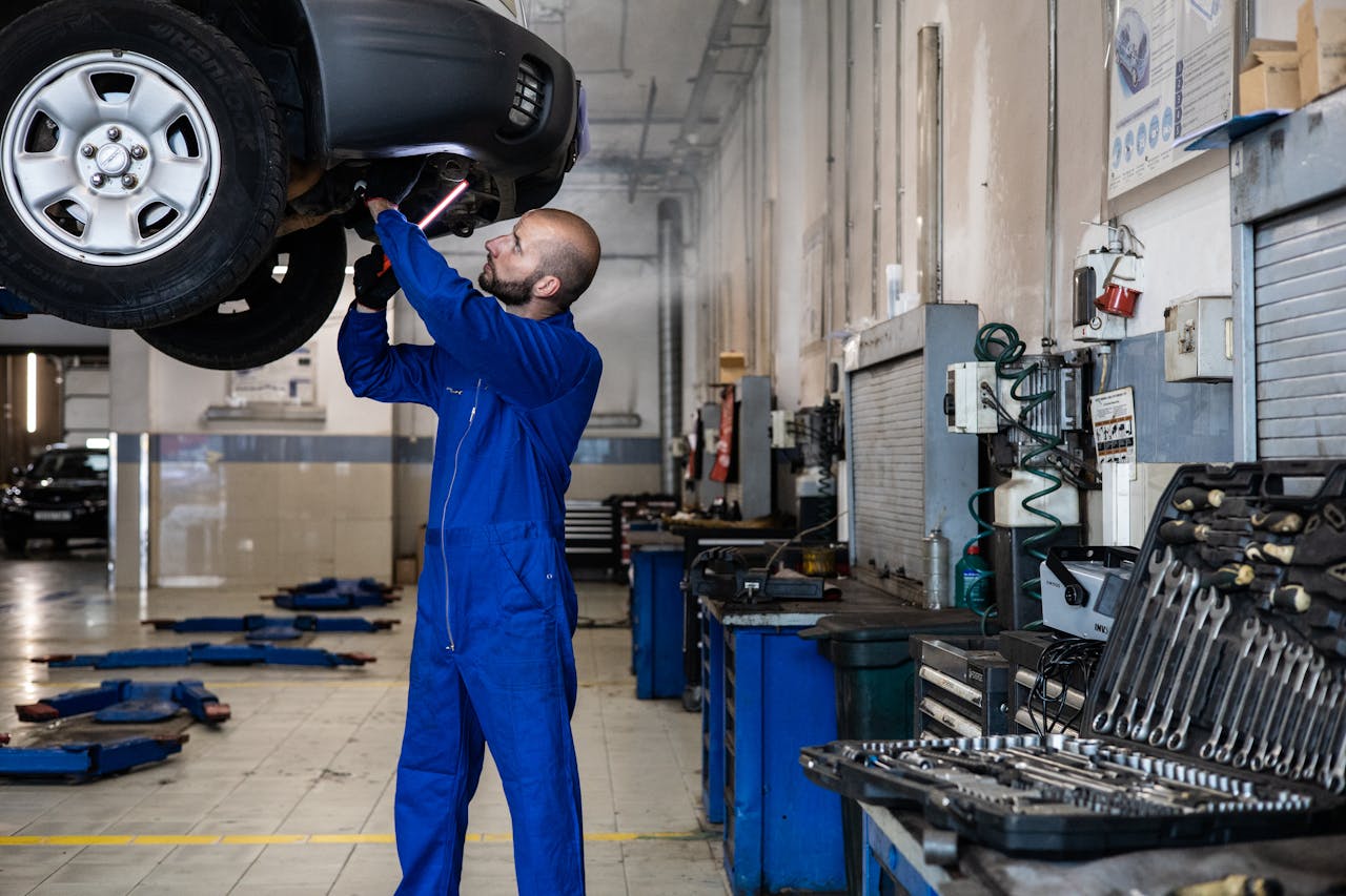 Home Mechanic inspecting a raised car in an auto workshop for maintenance and repair services.